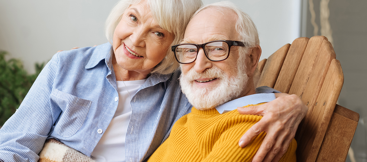 Pareja de personas mayores sonriendo, representando el bienestar y los cuidados apoyados en tecnología asistencial.